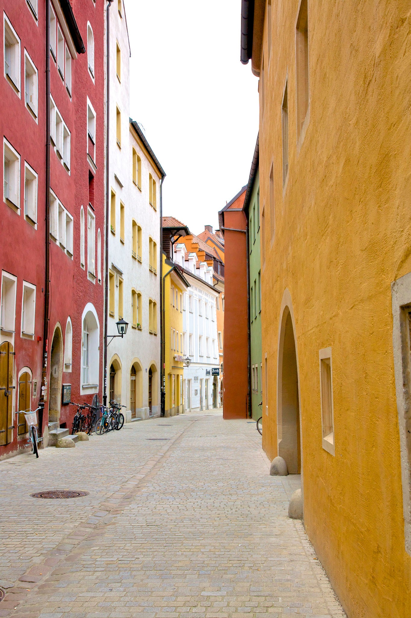 Colorful painted facades on charming cobblestone pedestrian street in Old Town of Regensburg, a Bavarian city on Danube River in southeast Germany.  Founded by Romans in 179 AD, Regensburg is one of Germany's oldest towns and is known for its well-preserved medieval core.