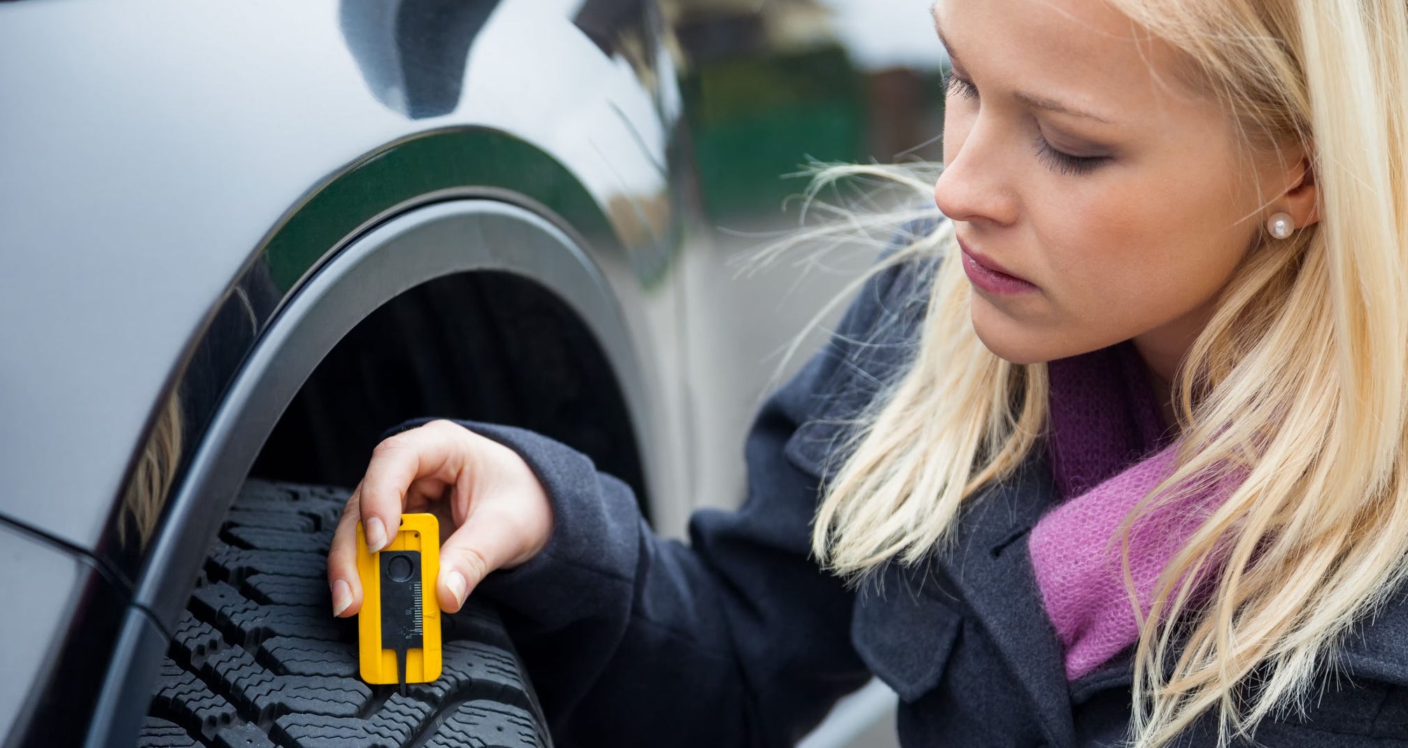 Woman checking a tire´s tread depth