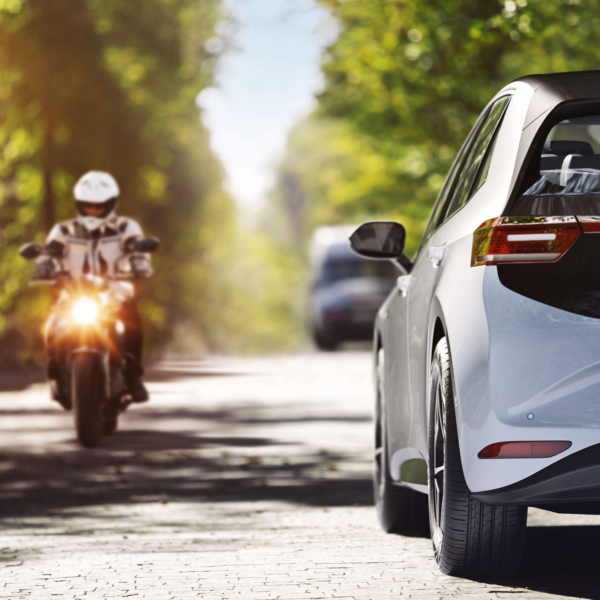 A motorbike and a passenger car pass each other