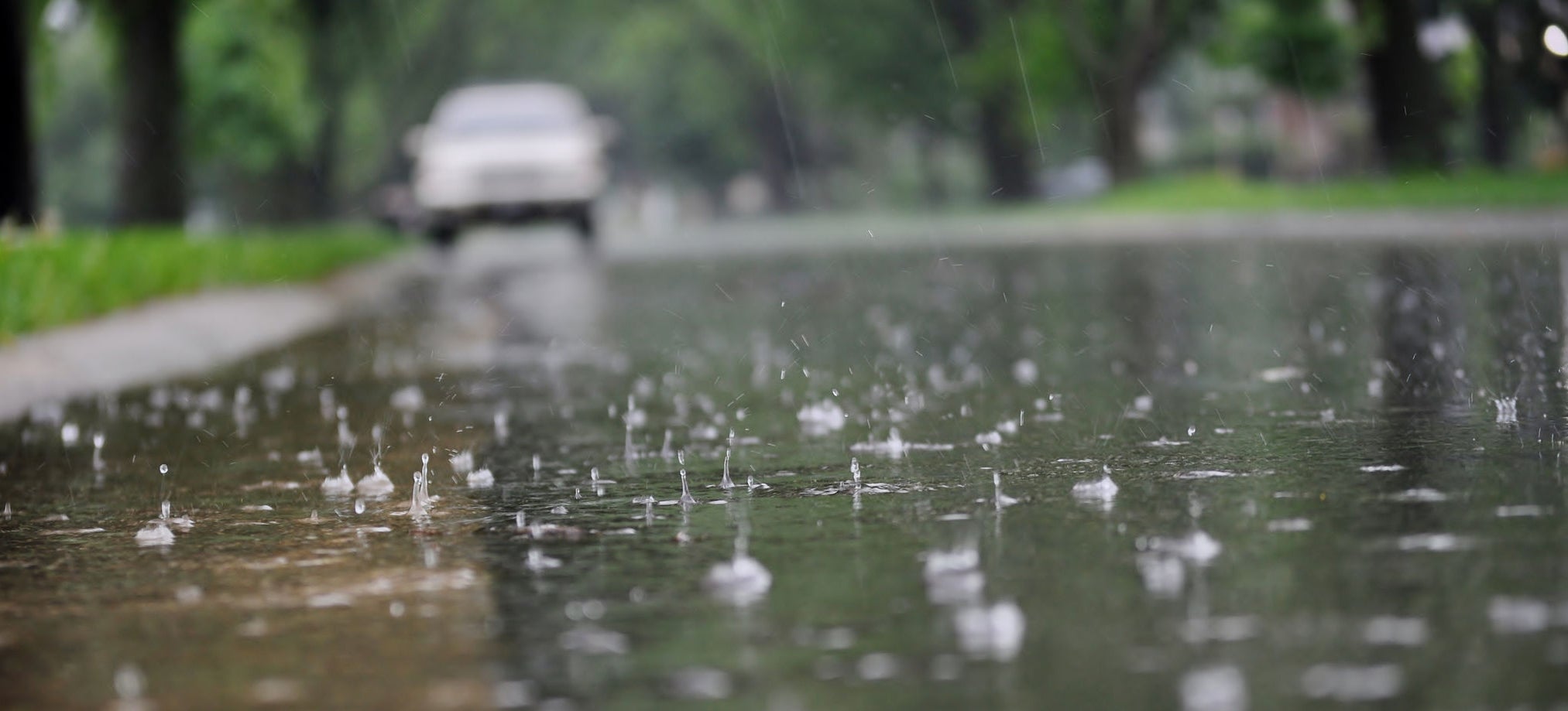 Water flowing along the street curb during heavy rain. Close up of splashing raindrops and air bubbles.