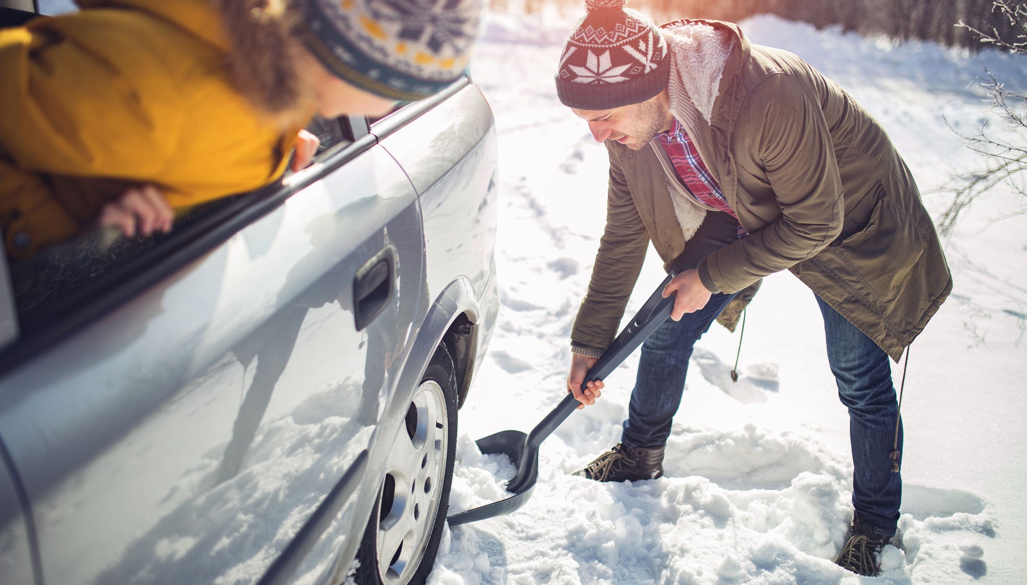 Photo of Man cleans snow near the car with shovel in nature