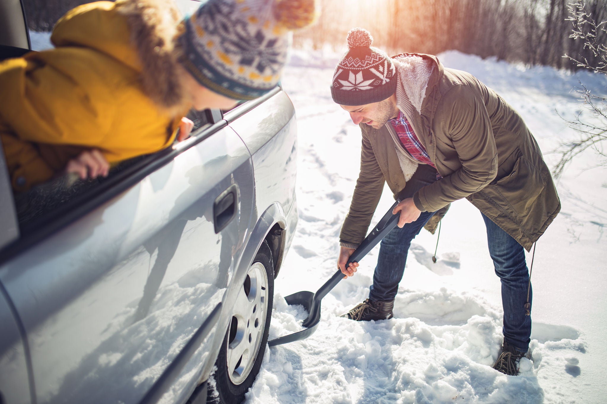 Photo of Man cleans snow near the car with shovel in nature