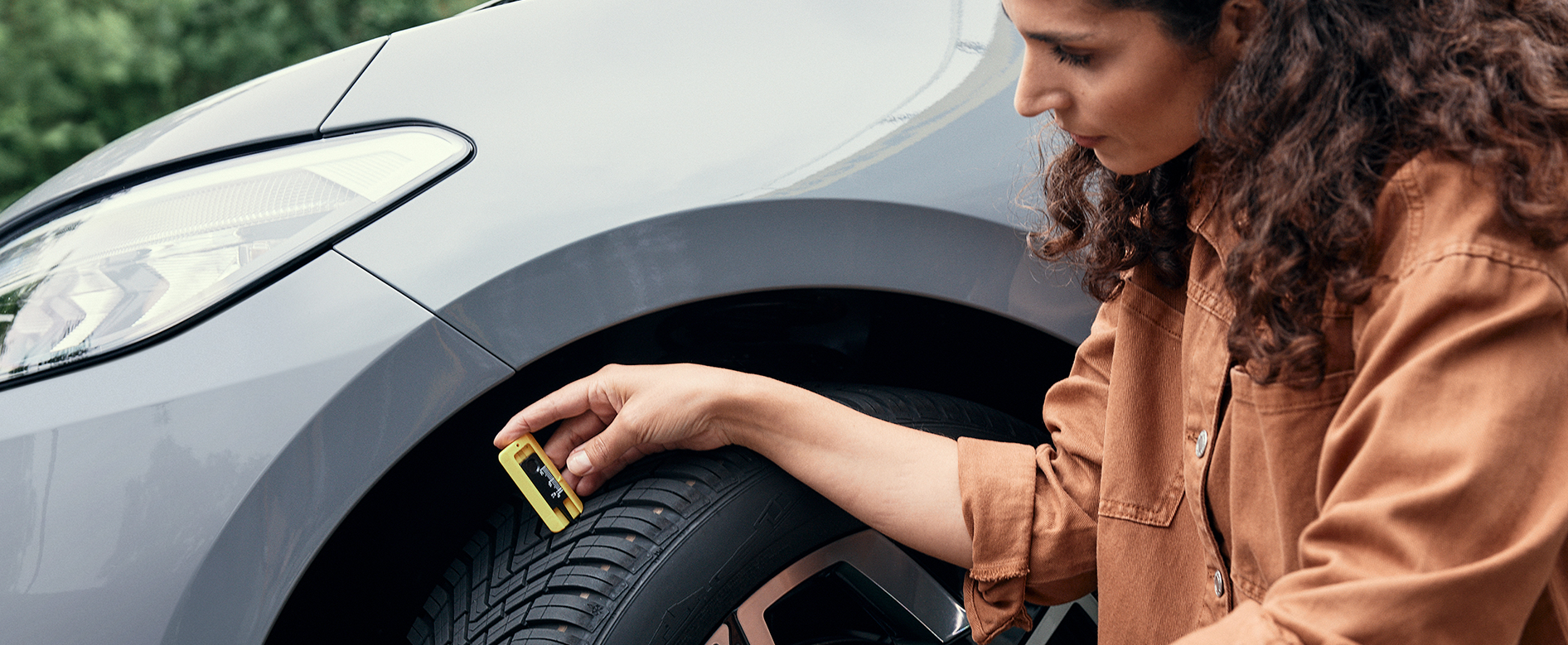 Woman checking her car´s tire tread depth