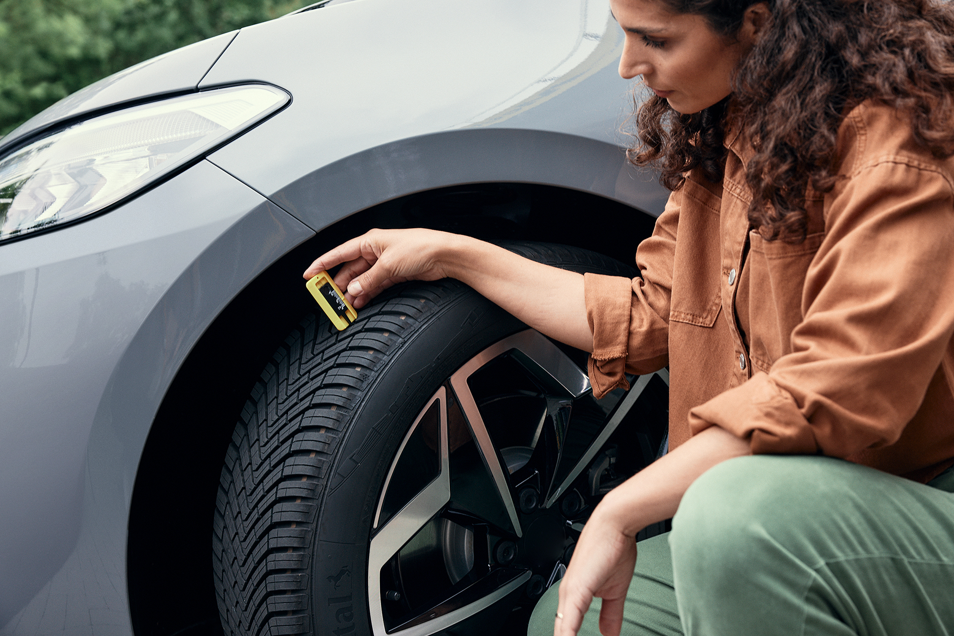 Woman checking her car´s tire tread depth